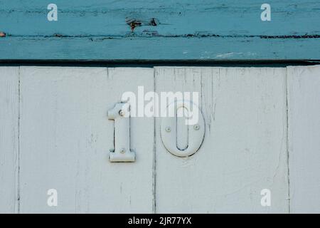 Die Zahl 10 an der Tür einer Strandhütte auf verwittertem Holz, verwittert schäbig schicke Tür mit der Zahl zehn 10 in aufgebrachten Ziffern an der Tür geschraubt. Stockfoto