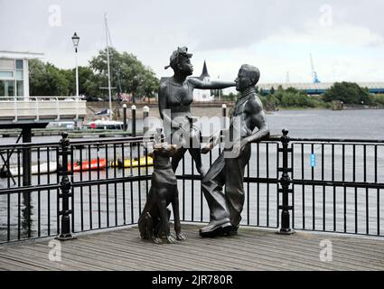 Leute wie wir - Statue Gruppe in Cardiff Bay. Sommer 2022. Cardiff Bay. August 2022. Norwegische Kirche im Hintergrund. Stockfoto