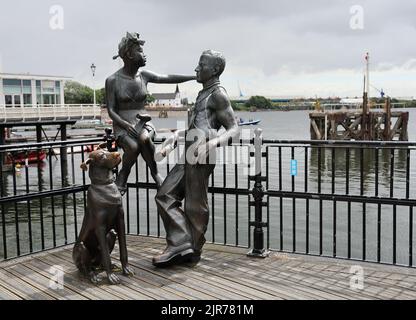 Leute wie wir - Statue Gruppe in Cardiff Bay. Sommer 2022. Cardiff Bay. August 2022. Norwegische Kirche im Hintergrund. Stockfoto