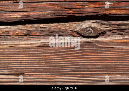 Makroaufnahme einer alten verwitterten dunkelbraunen gesprungenen Holzoberfläche mit schöner grober Maserung. Stockfoto
