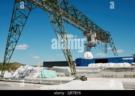 Teil einer riesigen Struktur oder Industriemaschine, die schwere weiße Säcke mit losen Rohstoffen hebt und sie in Reihen auf die Plattform legt Stockfoto