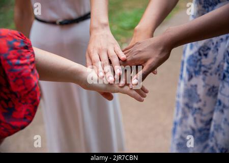 Die multiethnische Jugendgruppe im Park verbindet sich mit den Händen, um die Zweisamkeit zu manifestieren. Freundschaftskonzept. Stockfoto