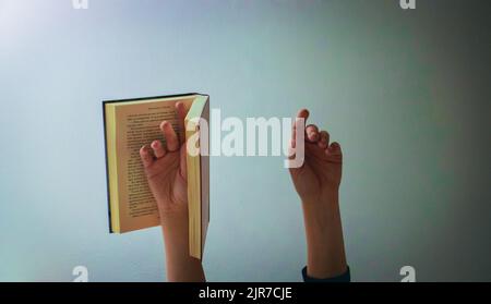 Weibliche Hand, eine mit einem Buch, Hände in der Luft, Kunstkonzept Stockfoto