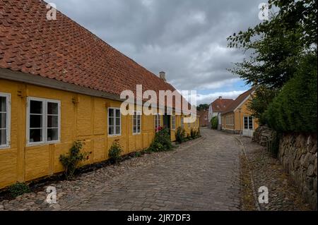 Gelbes, malerisches Fachwerkhaus in einer gepflasterten Straße in der dansih-Stadt Mariager, Dänemark, 6. August 2022 Stockfoto