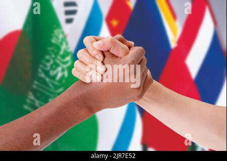 Hände von Menschen unterschiedlicher Ethik, die sich vor dem Hintergrund von Flaggen halten. Konzept von Beziehung, Vielfalt, Inklusion, Gemeinschaft, Zusammengehörigkeit. Stockfoto