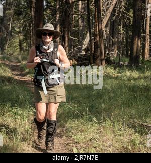 Wanderfrau mit breitem Krempenhut und hohen Gamaschen wandern im Wald im Yellowstone National Park Stockfoto