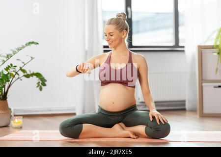 Glückliche, schwanger Frau, die zu Hause Yoga macht Stockfoto