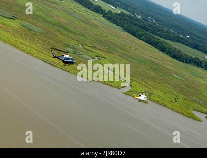 UH-1N Huey Heliopter, die der ersten Helicopter Squadron, Joint Base Andrews, MD., zugewiesen wurden, fliegen während des Trainings am 10. August 2022 über den Patuxent River, MD. 1 die Mission von HS besteht darin, eine vorrangige Luftbrücke für hochrangige zivile und militärische Führungskräfte auf nationaler Ebene in der Region der Hauptstadt zu schaffen. (USA Luftwaffe Foto von Master Sgt. Nicholikpriester) Stockfoto