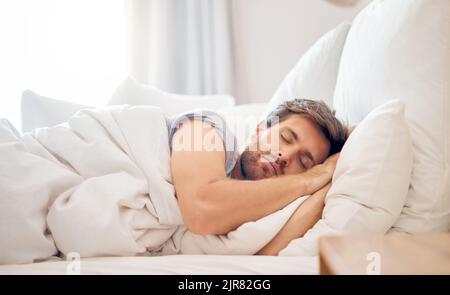 Haus, Schlafzimmer und schlafender Mann am Morgen, der seinen Kopf auf dem Kissen im Raum der Wohnung legte. Müde, Müdigkeit und entspannen männlich nehmen sich Zeit auf der Stockfoto