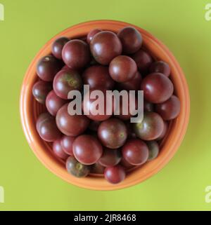 Eine Orange Schüssel voll mit schwarzen Kirschtomaten Stockfoto