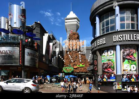 Niagara Falls, Kanada - 13. August 2022: Rainforest Cafe und andere Touristenattraktionen auf der belebten Straße Clifton Hill. Casino Niagara Tower kann sein Stockfoto