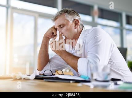 Ich könnte hier einschlafen. Ein reifer Geschäftsmann bläst seine Nase in das Büro. Stockfoto