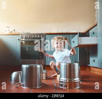Er möchte Schlagzeuger sein, wenn er erwachsen ist. Portrait eines entzückenden kleinen Jungen, der in der Küche mit Töpfen spielt. Stockfoto