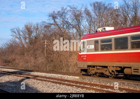 Bild eines Zuges, der die Stadt Banatsko novo selo, Serbien durchquert, betrieben von Srbija voz, der nationalen Personenbahn Serbiens. Stockfoto