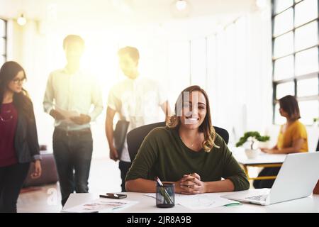 Ich habe alles im Kopf. Ein Porträt einer attraktiven jungen Frau, die in einem modernen Büro arbeitet, mit ihren Kollegen im Hintergrund. Stockfoto