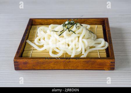 Gekühlte Zaru Udon, Nudeln mit geröstetem Seegras in einem Bambuskorb auf Holztablett serviert Stockfoto