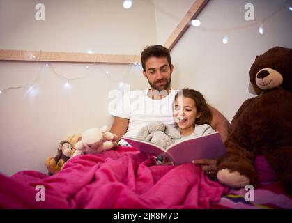 Shell haben viele magische Träume heute Abend. Ein Vater liest ein Buch mit seiner kleinen Tochter im Bett zu Hause. Stockfoto