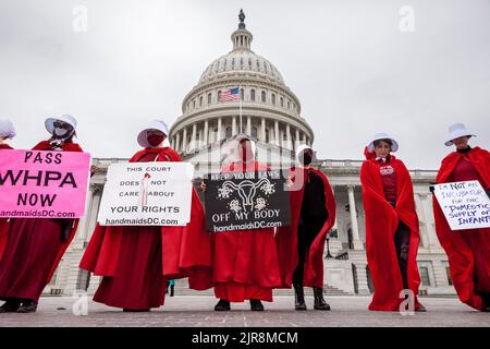 Washington, USA. 8.. Mai 2022. Demonstranten, die als Dienstmädchen aus der Geschichte der Dienstmädchen gekleidet sind, halten während des Protestes Plakate vor dem Kapitol. Die Handmaids Army DC kam nach Capitol Hill, um gegen die durchgesickerte vorläufige Entscheidung des Obersten Gerichtshofs zu protestieren, Roe v. Wade umzustürzen. (Bild: © Allison Bailey/SOPA Images via ZUMA Press Wire) Stockfoto