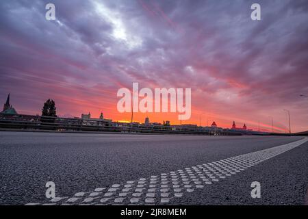 Zufahrtsstraße in die Stadt während des schönen, blutigen Sonnenuntergangs Stockfoto