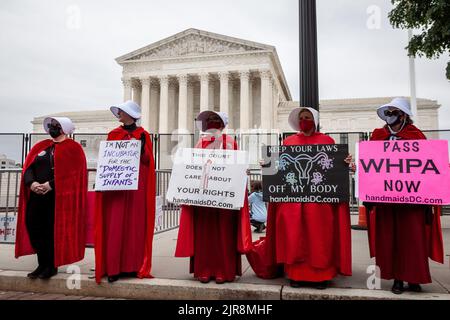 Washington, USA. 8.. Mai 2022. Demonstranten, die als Dienstmädchen von der Geschichte der Dienstmädchen gekleidet sind, halten während der Kundgebung Plakate vor dem Obersten Gerichtshof. Die Handmaids Army DC kam nach Capitol Hill, um gegen die durchgesickerte vorläufige Entscheidung des Obersten Gerichtshofs zu protestieren, Roe v. Wade umzustürzen. (Bild: © Allison Bailey/SOPA Images via ZUMA Press Wire) Stockfoto