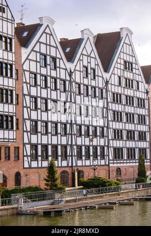 Danzig, Polen Mai 2022, moderne Gebäude über dem Motlawa-Fluss in der Altstadt. Tourismus auf dem Motlawa River. Neue Apartments-Architektur auf Granary Island Glasfenster mit Reflexionen. Touristisches Reiseziel Stockfoto