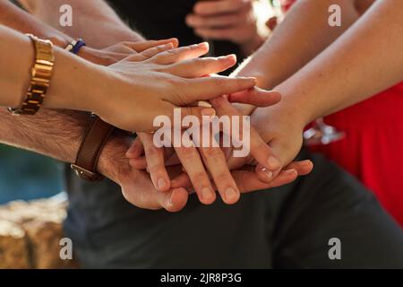 Eine Gruppe von nicht identifizierbaren Freunden, die ihre Hände auf einer Party im Freien in einen Stapel legen. Stockfoto