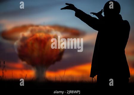 Das Konzept eines Atomstreiks. Silhouette eines Mannes in einem Anzug, der wie ein musikalischer Dirigent die Hände aufzwinkere. Ein Politiker, der einen Atomkrieg begann Stockfoto