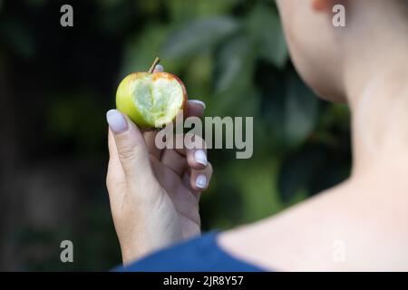 Frau, die einen gebissenen Apfel vor sich hält. Hochwertige Fotos Stockfoto