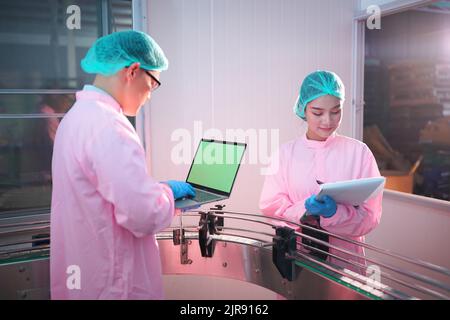 Asiatische Arbeiter arbeiten in Lebensmittel-und Getränke-Industrie-Fabrik mit Hygiene Arbeit Fruchtsaft Produktionslinie Inspektor Personal. Beve Prüfen Stockfoto