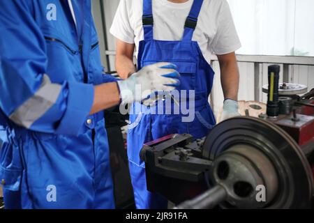 Arbeiter wechseln und reparieren Teile der Räder beim Autoservice Stockfoto
