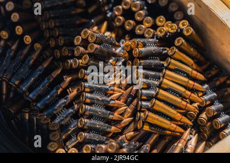 Nahaufnahme von glänzenden goldenen Büchsenbüchsen für Maschinengewehr, die in einer Holzkiste aufbewahrt werden. Munitionskonzept. Aufnahmebereich. Hochwertige Fotos Stockfoto