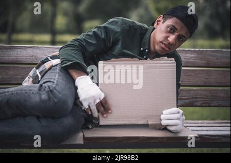 Mann, der Karton auf der Bank liegend hält Stockfoto