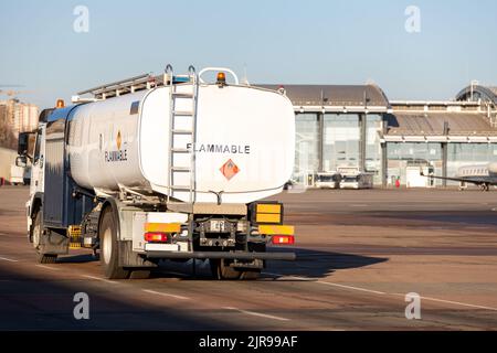 Rückansicht kleiner moderner Tankwagen, der auf dem Rollweg des Flugplatzes zum Betanken von Flugzeugen fährt. Zisterne LKW Luftfahrt Benzin. Gasversorgung des Flugzeugs Stockfoto