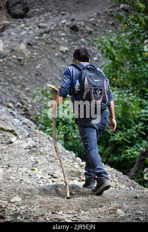 Januar 1. 2020 Uttarakhand INDIEN. Solo Wanderer mit einem Rucksack und Stick aufsteigend auf einem bergauf Trail. Stockfoto