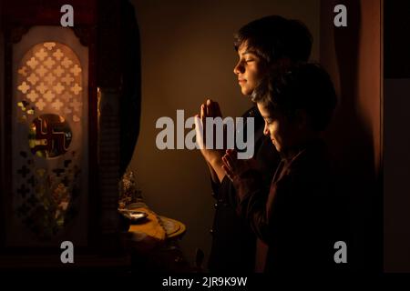 Portrait von zwei Brüdern, die mit gefalteten Händen zu Gott beten Stockfoto