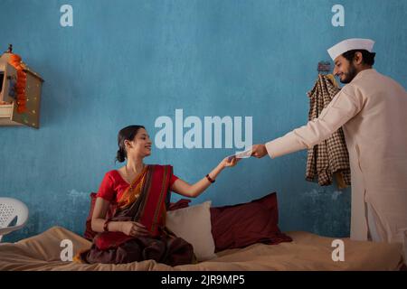 Maharashtrianerin spricht auf dem Smartphone, während ihr Mann daneben steht Stockfoto