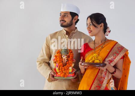 Maharashtrian Paar mit Statue von Lord Ganesh und Teller mit süßem Essen Stockfoto