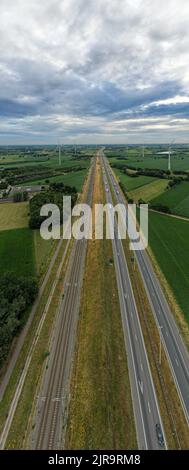 Brecht, Belgien, 6.. Juli 2022, Panorama-Drohnenansicht von Windpark oder Windpark, mit hohen Windkraftanlagen zur Stromerzeugung mit der Autobahn mit wenigen Autos und Eisenbahn daneben, in der Nähe der Ausfahrt von Brecht in Belgien, Europa. Hochwertige Fotos Stockfoto