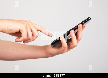 Frau mit der Hand auf dem Telefonbildschirm. Frau, die einen Anruf entgegennimmt, Smartphone-Anwendungen verwendet, Notizen macht. Hochwertige Fotos Stockfoto