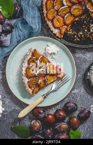 Hausgemachter Pflaumenkuchen mit Zuckerpulver auf dem Küchentisch aus Stein Stockfoto