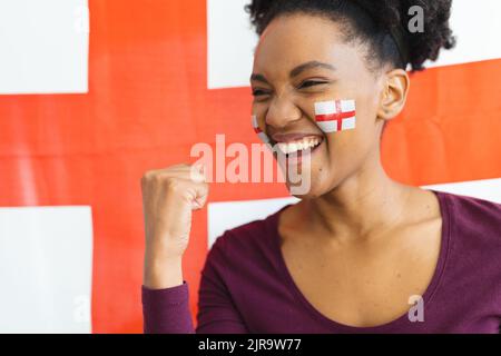 Bild einer glücklichen afroamerikanischen Frau mit Flaggen englands auf dem Gesicht über der Flagge englands Stockfoto