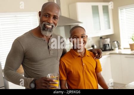 Porträt eines glücklichen afroamerikanischen männlichen Teenagers mit seinem Vater in der Küche Stockfoto