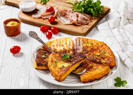 Nahaufnahme von Kartoffelfarbe, Irish Potato Cakes, Kartoffelbrot auf weißem Teller auf weißem Holztisch mit Speck, Tomaten und Petersilie im Hintergrund Stockfoto