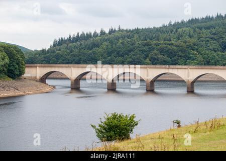 Der Ladybower Stausee während des trockenen und trockenen Wetters im Sommer 2022. Das Bild zeigt den Blick auf die Brücke von Ashopton, wo sich die A57 kreuzt, die Markierungen auf der Brücke zeigen den üblichen Wasserstand. Ladybower Reservoir ist ein großes Y-förmiges, künstliches Reservoir, das niedrigste von drei im Upper Derwent Valley in Derbyshire, England. Stockfoto