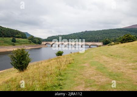 Der Ladybower Stausee während des trockenen und trockenen Wetters im Sommer 2022. Das Bild zeigt den Blick auf die Brücke von Ashopton, wo sich die A57 kreuzt, die Markierungen auf der Brücke zeigen den üblichen Wasserstand. Ladybower Reservoir ist ein großes Y-förmiges, künstliches Reservoir, das niedrigste von drei im Upper Derwent Valley in Derbyshire, England. Stockfoto