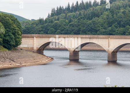 Der Ladybower Stausee während des trockenen und trockenen Wetters im Sommer 2022. Das Bild zeigt den Blick auf die Brücke von Ashopton, wo sich die A57 kreuzt, die Markierungen auf der Brücke zeigen den üblichen Wasserstand. Ladybower Reservoir ist ein großes Y-förmiges, künstliches Reservoir, das niedrigste von drei im Upper Derwent Valley in Derbyshire, England. Stockfoto