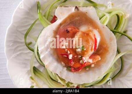 Jakobsmuscheln in süßer Chilisauce auf Gurkenbett. Stockfoto