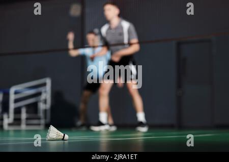 Federball auf dem Gerichtssaal, Paar spielt im Hintergrund Stockfoto