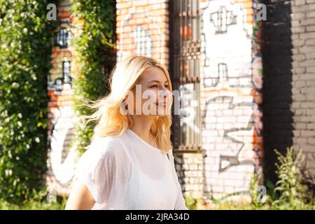 Junge schöne Blondine auf der Straße der städtischen Kunst Raum. Das Konzept der Schaffung eines Kunstraums und Festivals in verlassenen Gebäuden. Altes Gebäude. Stockfoto