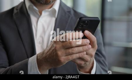 Bewegte Aufnahmen aus nächster Nähe männliche Hände halten Smartphone Erwachsene 40s Mann mit Mobiltelefon in Innenräumen. Bärtiger Geschäftsmann, Technologie-Nutzer, der im digitalen Bereich arbeitet Stockfoto